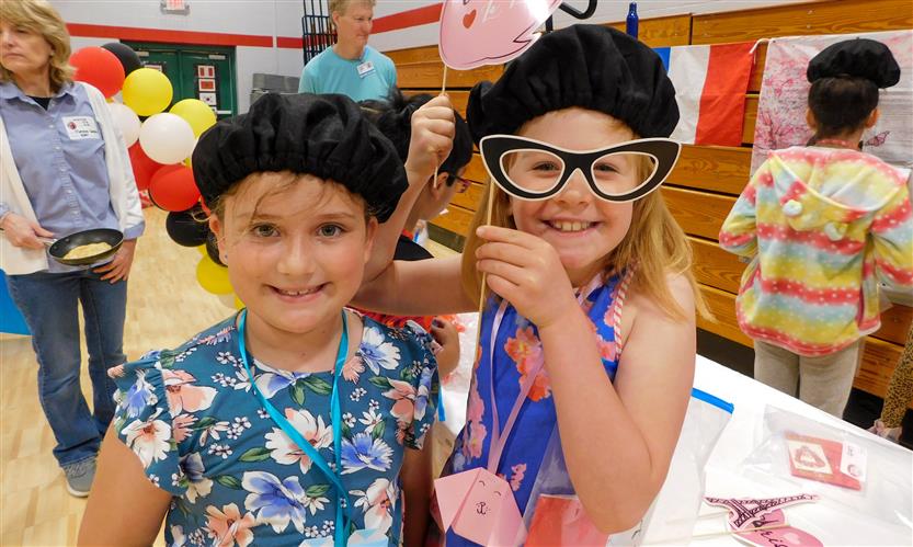 Two girls wearing berets smile